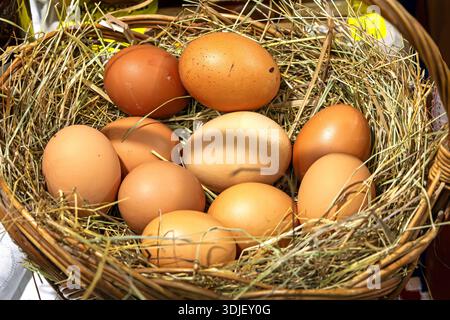 Uova di pollo fresche biologiche allevate all'aperto nel cestino in rattan venduto sul mercato locale Foto Stock