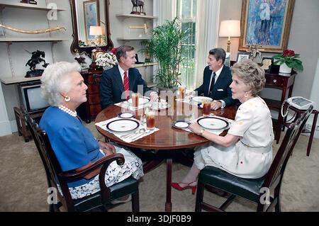 Il Presidente degli Stati Uniti Ronald Reagan e la First Lady Nancy Reagan pranzano con il Vice Presidente degli Stati Uniti George H. W. Bush e la Second Lady Barbara Bush nello studio del White House Oval Office, Washington, D.C., USA, il Presidente Ronald Reagan White House Photographic Office, 11 agosto 1988 Foto Stock