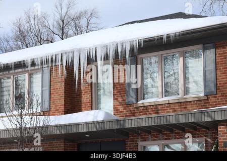 Primo piano della casa con ghiaccioli appesi alle grondaie Foto Stock