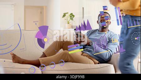 Uomo sdraiato che utilizza lo smartphone sul divano beige di casa, con donna in maglione giallo, sovrapposizioni dati Foto Stock