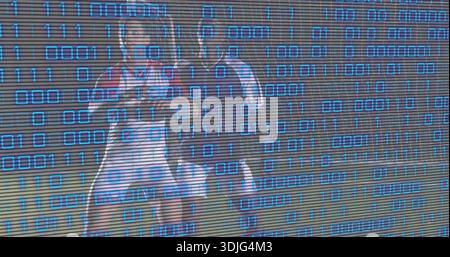 In piedi due giocatori di calcio che indossano caschi e piazzole sul campo dello stadio, con sovrapposizione binaria blu. Atleti, outfit, uniforme, outdoor, notte, digitale, c Foto Stock