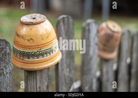 Vecchi vasi in ceramica rustici fatti a mano sulla recinzione in legno sul lato campagna. Foto Stock