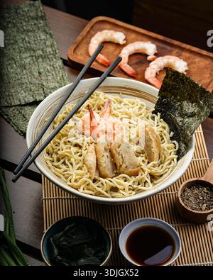 Un'inquadratura ad alto angolo presenta una gustosa ciotola di ramen fumante, traboccante di noodle teneri, succulenti gamberi, salate torte di pesce e alghe croccanti. Foto Stock