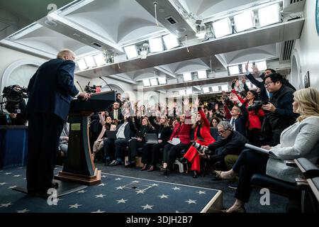 Il presidente Donald Trump parla sul podio con i giornalisti che alzano la mano in una sala stampa affollata Foto Stock