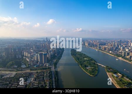 Changsha City, Cina: La vista aerea rivela un vasto paesaggio urbano. Un ampio fiume scorre attraverso, caratterizzato da una lunga isola verde in mezzo a molti edifici della città Foto Stock