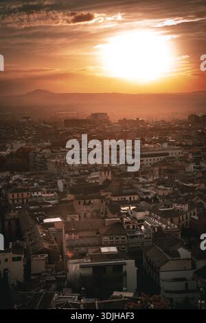 La vista di un tramonto dorato getta lunghe ombre sui tetti intricati e sugli edifici storici, dipingendo la città con tonalità calde, Granada, Andalusia, S. Foto Stock