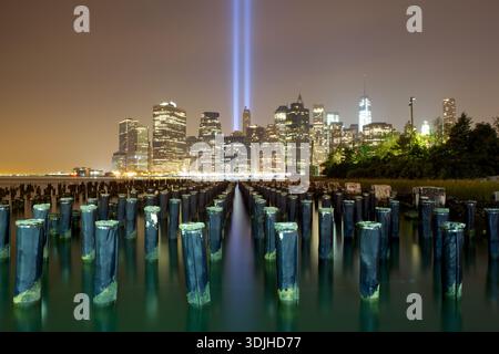 Vista dal suolo del Tribute in Light che illumina il cielo notturno sullo skyline della città e sull'iconico Ponte di Brooklyn, New York, Stati Uniti. Foto Stock