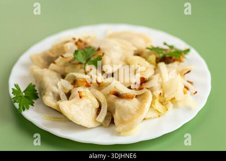 Gnocchi fatti in casa con cipolle fritte serviti su un piatto bianco. Foto Stock
