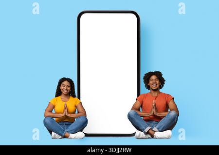 Coppia nera rilassata seduta da smartphone enorme con schermo vuoto Foto Stock