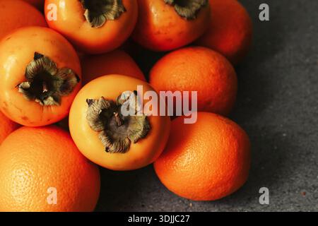 Primi piani di sosia e arance fresche. Fondo di frutta matura di stagione. Cibo sano e naturale ricco di vitamine. Consistenza dei frutti del raccolto autunnale. Foto Stock