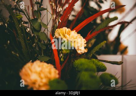 Composizione floreale Moody con garofani arancioni e crisantemi verdi. Foto Stock
