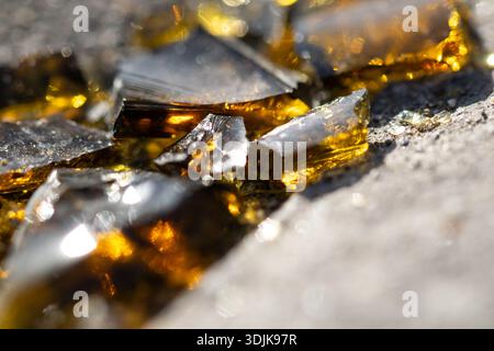 un'immagine macro in primo piano di una bottiglia di birra in vetro marrone frantumata sul pavimento Foto Stock