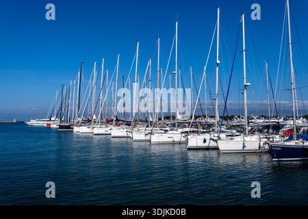 Una lunga fila di barche a vela bianche è ormeggiata nel porto di Novigrad sotto un cielo azzurro. Foto Stock