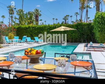 Tavolo sul patio esterno per cene e feste diurne con vista sul cortile della piscina a Palm Springs, California Foto Stock