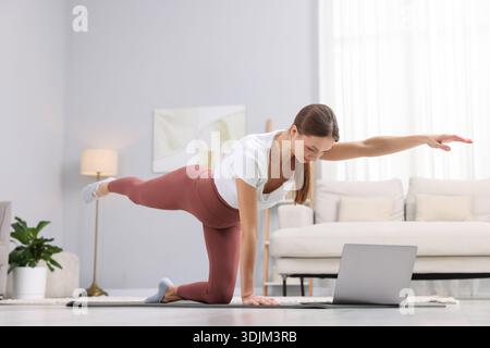 Donna incinta che ha una lezione di yoga online via laptop a casa Foto Stock