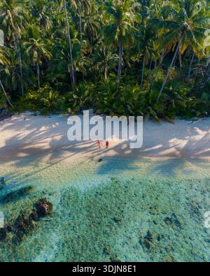 Scopri la bellezza della spiaggia di Takhian a Koh Kood, Thailandia. Goditi le onde dolci, la sabbia soffice e le palme vivaci. Un paio di uomini e una donna lo sono Foto Stock