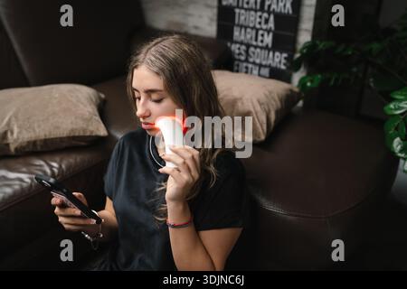 Donna seduta comodamente a rivedere le registrazioni podcast con le cuffie Foto Stock