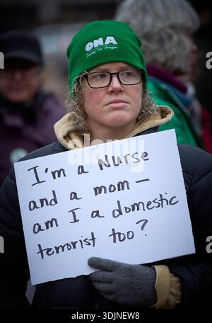 Una donna ha un segno come infermiere e altri ricordano Alex Pretti in una veglia a lume di candela a Eugene, Oregon, 27 gennaio 2026. Foto Stock