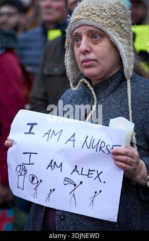 Una donna ha un segno come infermiere e altri ricordano Alex Pretti in una veglia a lume di candela a Eugene, Oregon, 27 gennaio 2026. Foto Stock