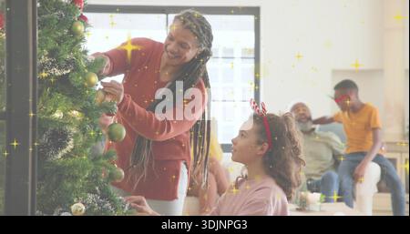 Mettere la donna in maglione ruggine e la bambina appesa a baule verdi sull'albero di Natale di casa Foto Stock
