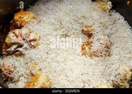 Cottura del pilaf: Riso bianco aggiunto alle polpette e all'aglio in una pentola. Preparazione tradizionale di piatti a base di cereali. Foto Stock