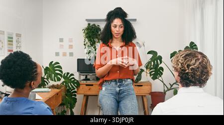 Confident Young Woman si presenta oggi a Una piccola riunione del team di Modern Tech Office Foto Stock