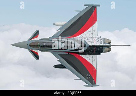 Immagine aria-aria di un Eurofighter EF-2000 Typhoon dell'aeronautica militare tedesca, immatricolazione 30+25, seriale GS015, assegnato al Taktisches Luftwaffengeschwader 71. L'aereo porta lo schema di vernice commemorativo Spirit of Richthofen con la coda rossa ispirata al Barone Rosso. Alimentato da due motori turbofan Eurojet EJ200, il caccia multiruolo è mostrato in banca con una vista ravvicinata del cockpit e del pilota durante un volo in esposizione al Royal International Air Tattoo nel 2019. Foto Stock