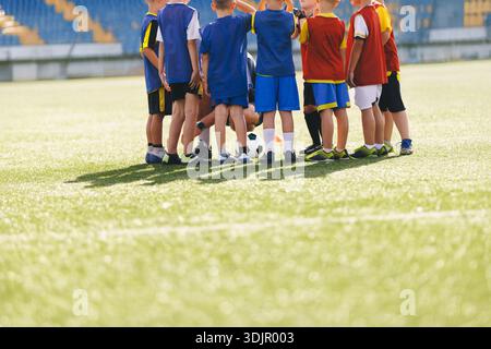 Squadra giovanile di calcio Huddle on Field; i bambini si radunano prima della partita mostrando lavoro di squadra e sportività Foto Stock