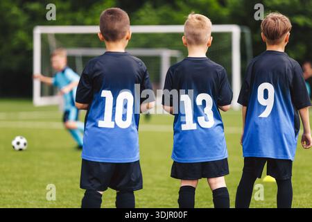 Formazione delle squadre giovanili di calcio da dietro. Bambini che indossano maglie numerate prima della partita di calcio Foto Stock