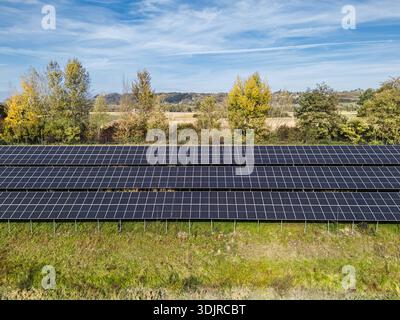 I pannelli solari coprono i terreni in un campo, generando energia rinnovabile e sostenendo l'azione per il clima. Foto Stock