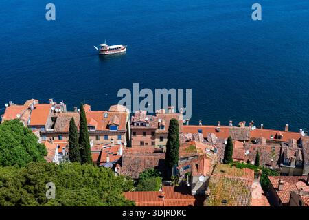 Vista dall'alto dal Campanile della Chiesa di Sant'Eufemia sulle case dai tetti rossi e su una piccola barca sul mare Adriatico blu in lontananza. Ro Foto Stock