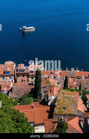 Vista dall'alto dal Campanile della Chiesa di Sant'Eufemia sulle case dai tetti rossi e su una piccola barca sul mare Adriatico blu in lontananza. Ro Foto Stock