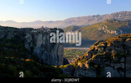 Il Monastero della Santissima Trinità, arroccato su una torreggiante roccia di Meteora all'alba, con catene montuose che svaniscono in lontananza, Tessaglia, Grecia Foto Stock