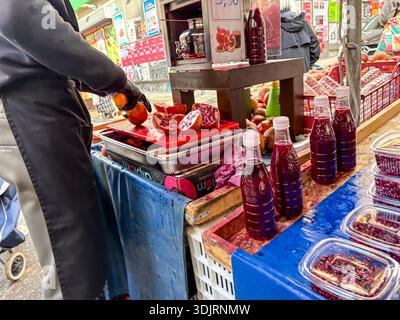 Mercato di Kallidromiou (Λαϊκή Αγορά). Venditore che prepara bottiglie di succo di melograno fresco al famoso mercato di Exarcheia, Atene, Grecia. Foto Stock