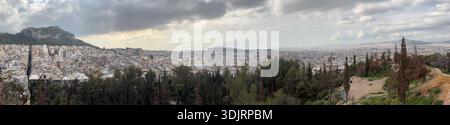 Vista panoramica di Atene dal Colle Strefi. Mostra l'ampia città moderna, l'Acropoli e il Colle di Licabetto sotto il cielo nuvoloso. Foto Stock