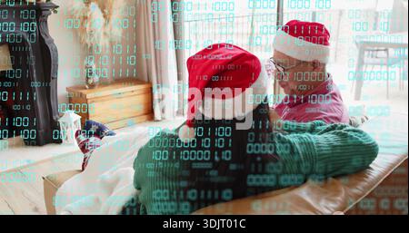 Una coppia seduto appoggiata sul divano nel soggiorno, con rivestimento binario e cappelli di Babbo Natale Foto Stock
