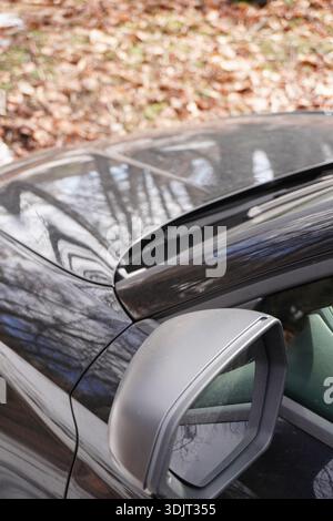 Primo piano dello specchietto laterale di un'auto. Macchina parcheggiata. Viaggiando in auto. Automobile nera, vista ravvicinata, immagine ritagliata. Foto Stock