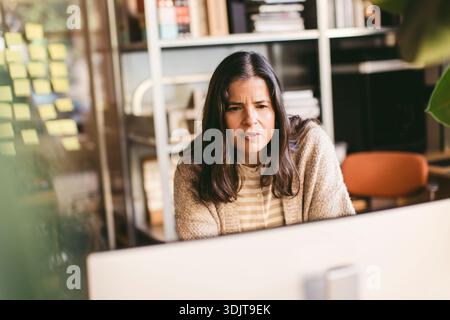 Esperta di design donna matura e premurosa che lavora al computer in ufficio Foto Stock