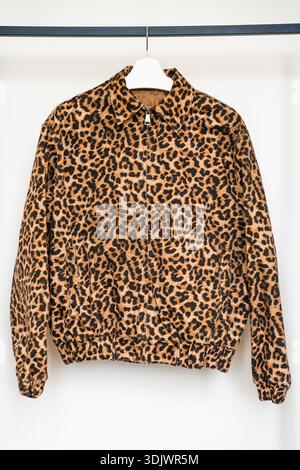 Bomber in cotone con stampa leopardata su appendiabiti isolato su sfondo bianco minimalista Foto Stock