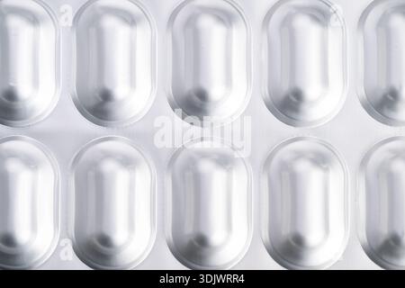 confezione blister vuota per primo piano che mostra cavità di lamina metallica e pillole, superficie riflettente, estetica clinica sterile, illuminazione soffusa da studio, macro compos Foto Stock
