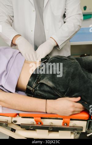 L'urologo esamina i reni di pazienti maschi sdraiati per rilevare il dolore e le dimensioni Foto Stock