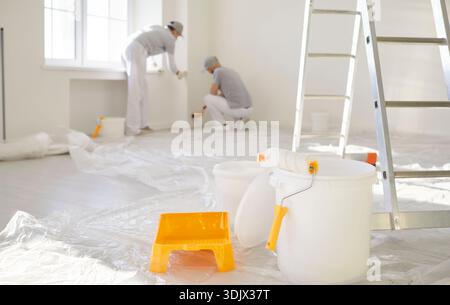 I pittori rinnovano gli interni luminosi, dipingendo le pareti con rullo, scala e secchio Foto Stock