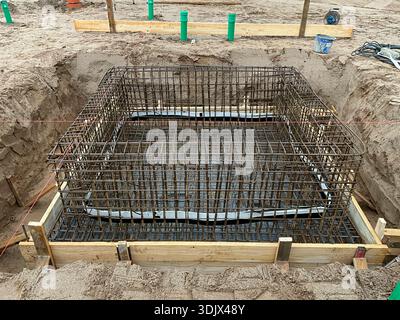 Gabbia per armature in acciaio installata in una fossa di scavo quadrata per un fondamento in cemento armato. L'immagine mostra una reinfo in acciaio assemblato con precisione Foto Stock