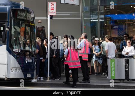 I passeggeri attendono di salire a bordo di un autobus Auckland Transport presso una trafficata fermata nel centro di Auckland, nuova Zelanda. Foto Stock
