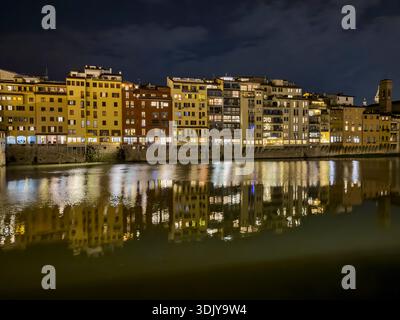 Vista notturna degli edifici lungo il fiume Arno con riflessi sull'acqua - Firenze, Italia Foto Stock
