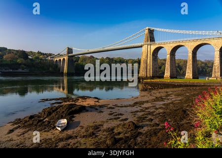 Ampia vista dello storico ponte sospeso Menai che getta ombre sullo stretto di Menai nel Galles del Nord Foto Stock