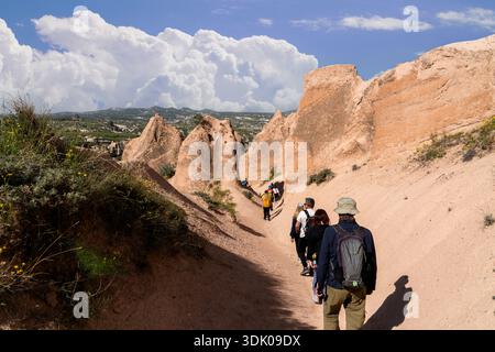 I turisti camminano su un sentiero tra massicce formazioni rocciose nelle valli uniche di Goreme, Turchia Foto Stock