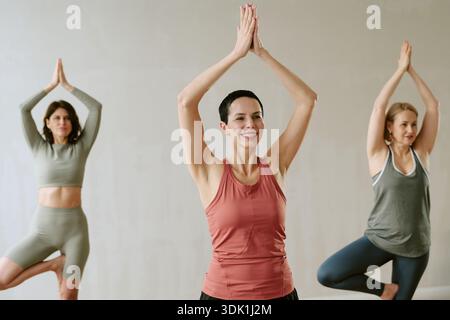 Gruppo di donne di mezza età che praticano lo Yoga pone insieme in interni Foto Stock