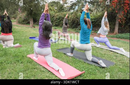 Donne che fanno esercizi di yoga all'aperto nel parco cittadino - stile di vita sano e concetto di sport - attenzione principale sul corpo femminile con felpa blu Foto Stock