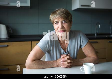 Portret donna anziana felice in cucina sta guardando la macchina fotografica. positivo. Concetto di stile di vita felice || modello rilasciato Foto Stock